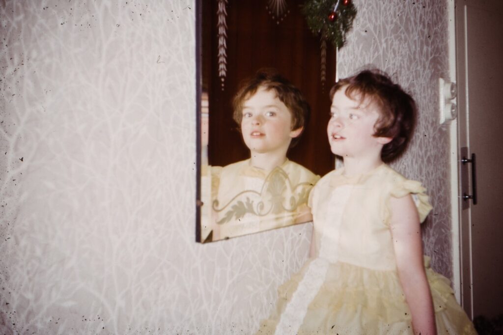 Image of young girl in a yellow dress looking sideways n a mirror